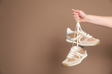 Photo of Woman with stylish sneakers on light brown background, closeup. Space for text