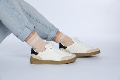 Woman wearing stylish sneakers on white background, closeup