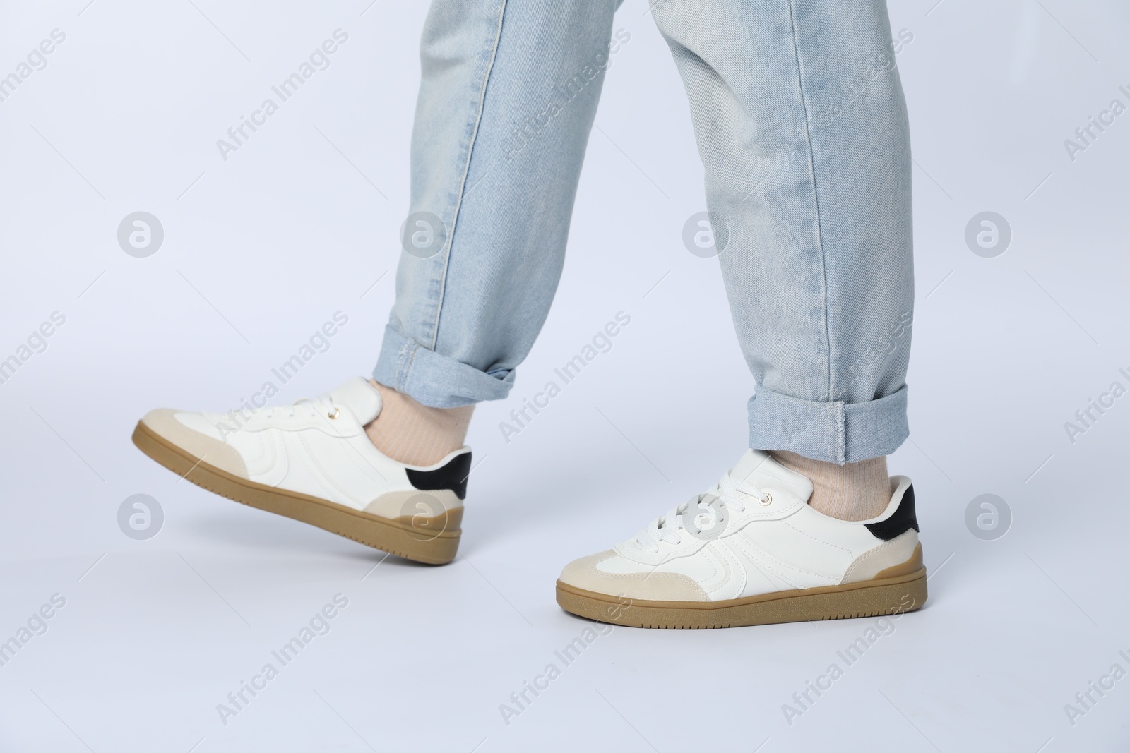 Photo of Woman wearing stylish sneakers on white background, closeup