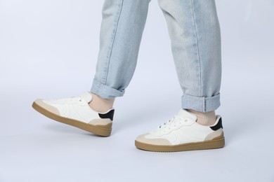 Photo of Woman wearing stylish sneakers on white background, closeup