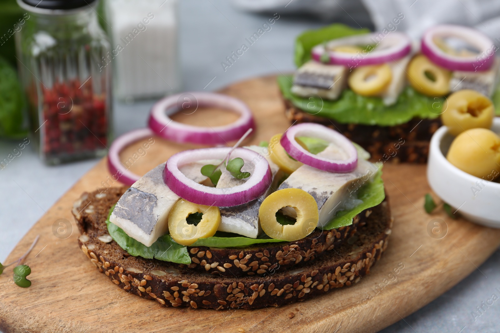 Photo of Tasty sandwiches with herring, onions and olives on table, closeup