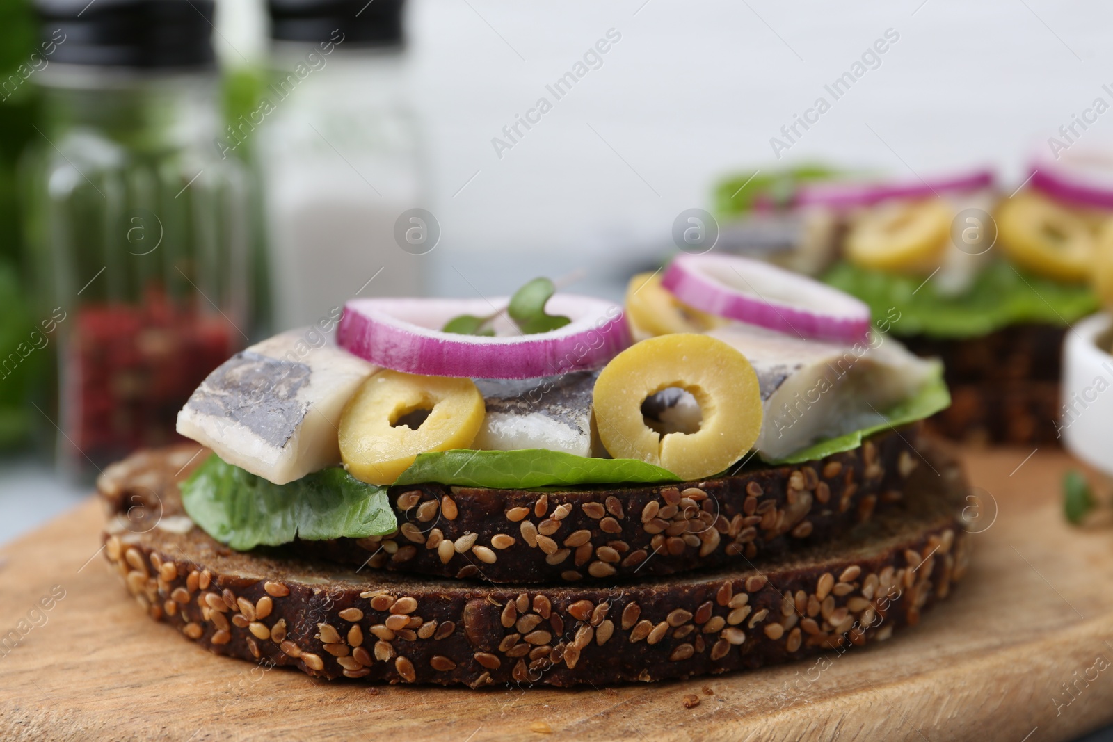 Photo of Tasty sandwich with herring, onion and olives on table, closeup