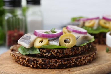 Tasty sandwich with herring, onion and olives on table, closeup