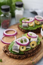 Tasty sandwiches with herring, onions and olives on table, closeup