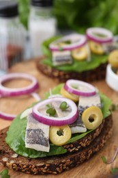 Tasty sandwiches with herring, onions and olives on table, closeup