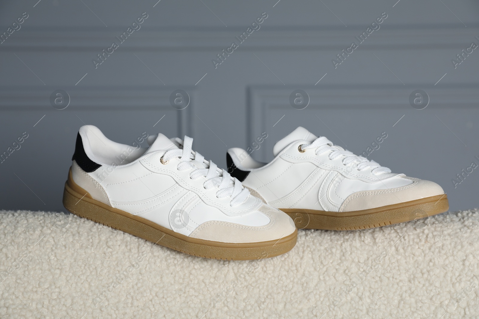 Photo of Pair of stylish sneakers on light fabric surface