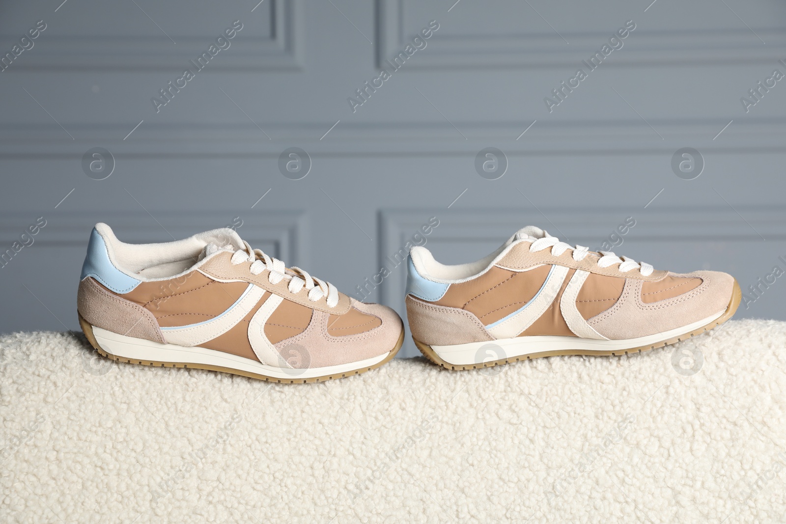 Photo of Pair of stylish sneakers on light fabric surface