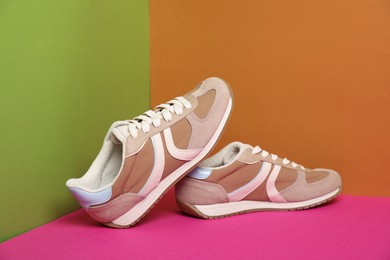 Pair of stylish sneakers on color background