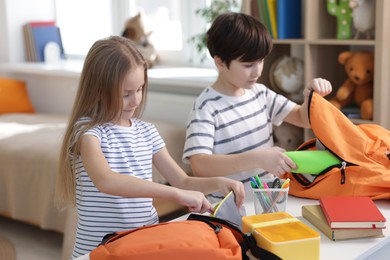 Photo of Kids getting ready for school at table indoors