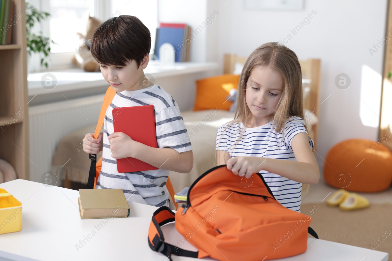 Photo of Kids getting ready for school at table indoors