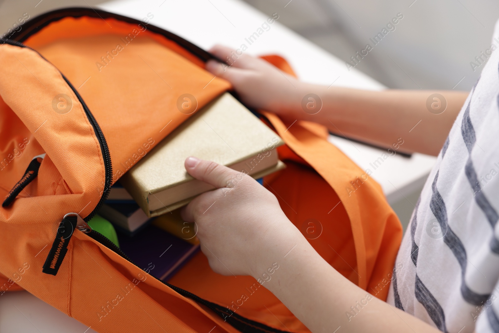 Photo of Boy packing backpack for school at home, closeup