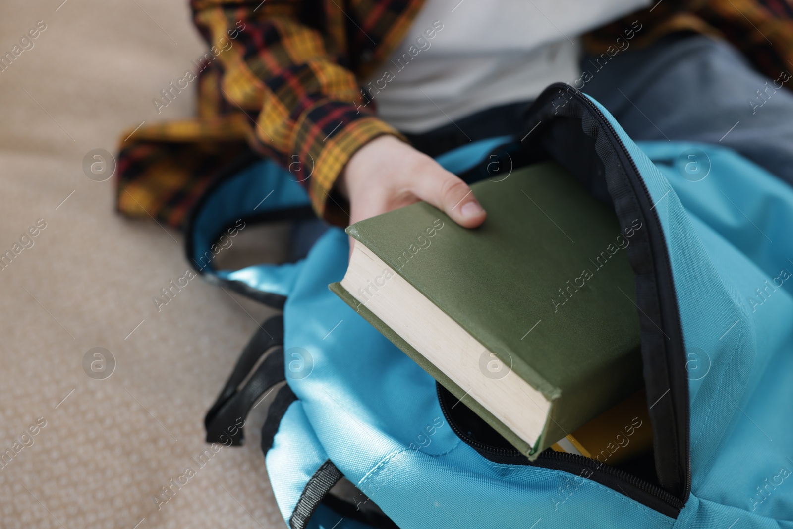 Photo of Boy packing backpack for school at home, closeup