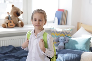 Portrait of little girl with backpack at home