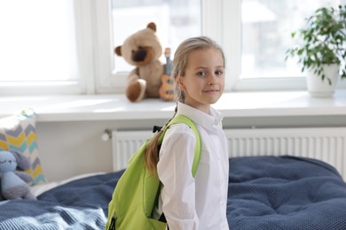 Portrait of little girl with backpack at home