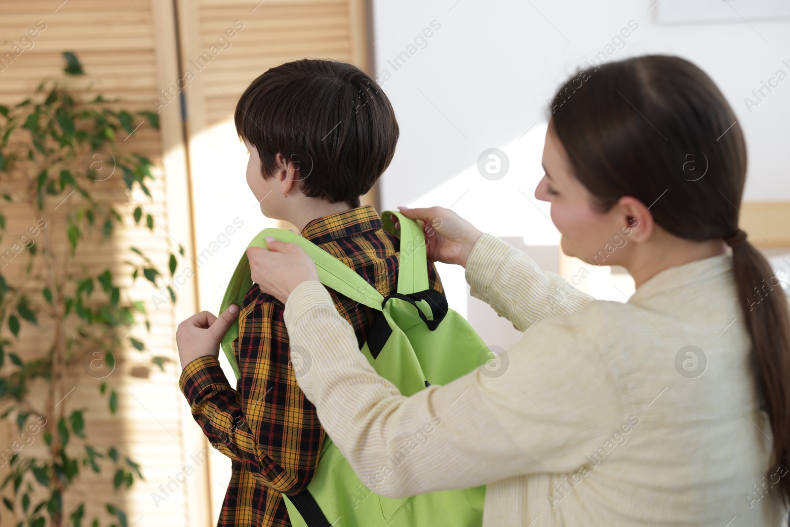 Photo of Mother helping her son get ready for school at home