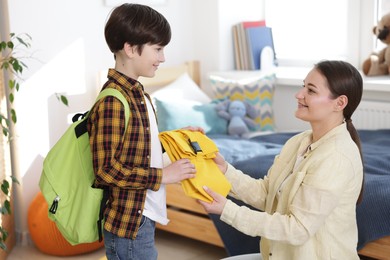 Photo of Mother helping her son get ready for school at home