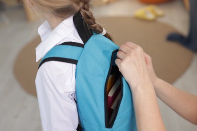 Mother helping her daughter get ready for school at home, closeup