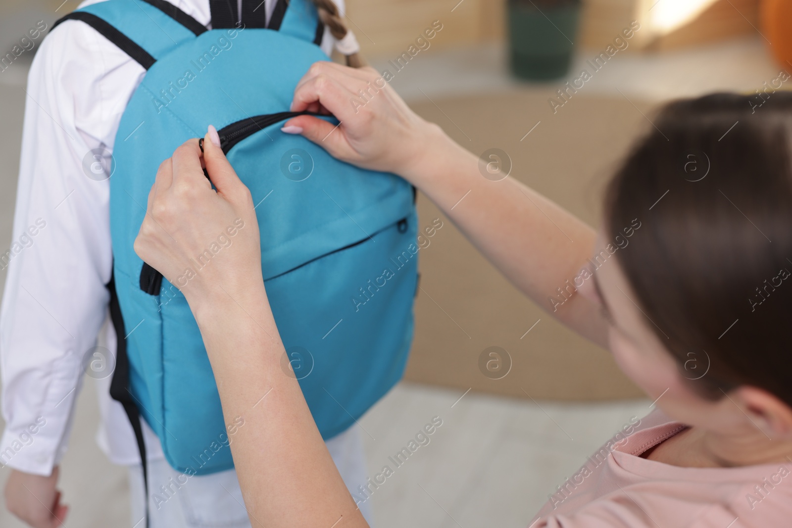 Photo of Mother helping her daughter get ready for school at home, closeup