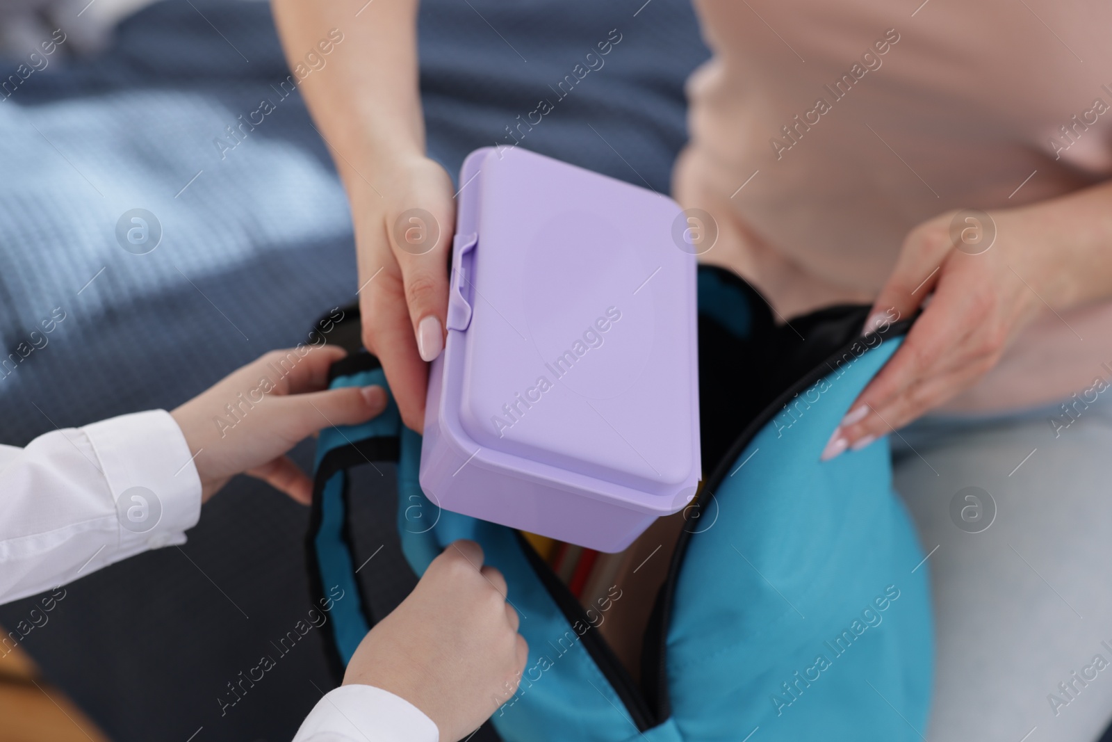 Photo of Mother packing her daughter's lunch at home, closeup