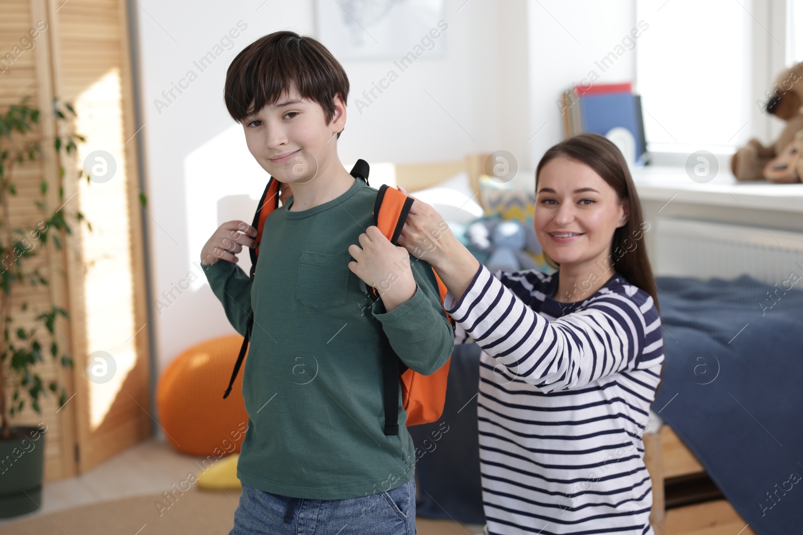 Photo of Mother helping her son get ready for school at home