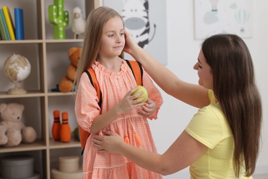 Mother helping her daughter get ready for school at home