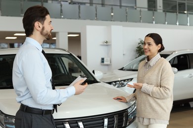 Happy salesman and client near new car in salon