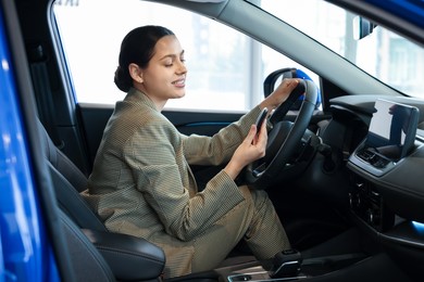 Photo of Happy woman with key inside new car in salon