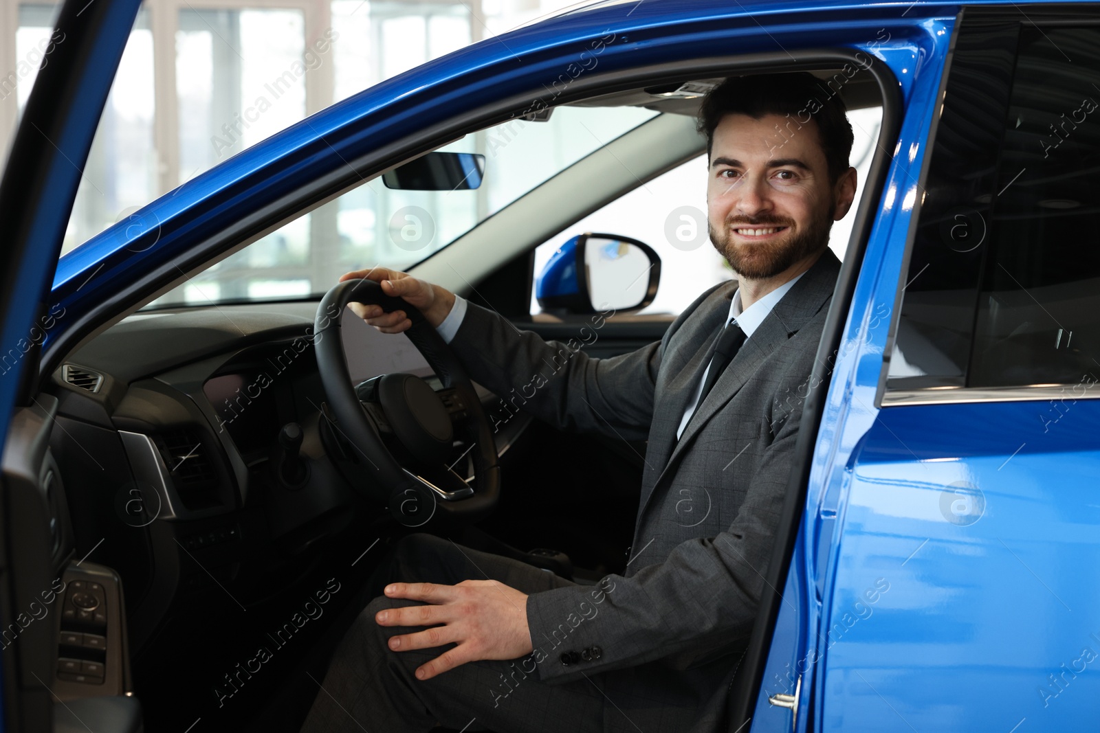 Photo of Happy man inside new blue car in salon