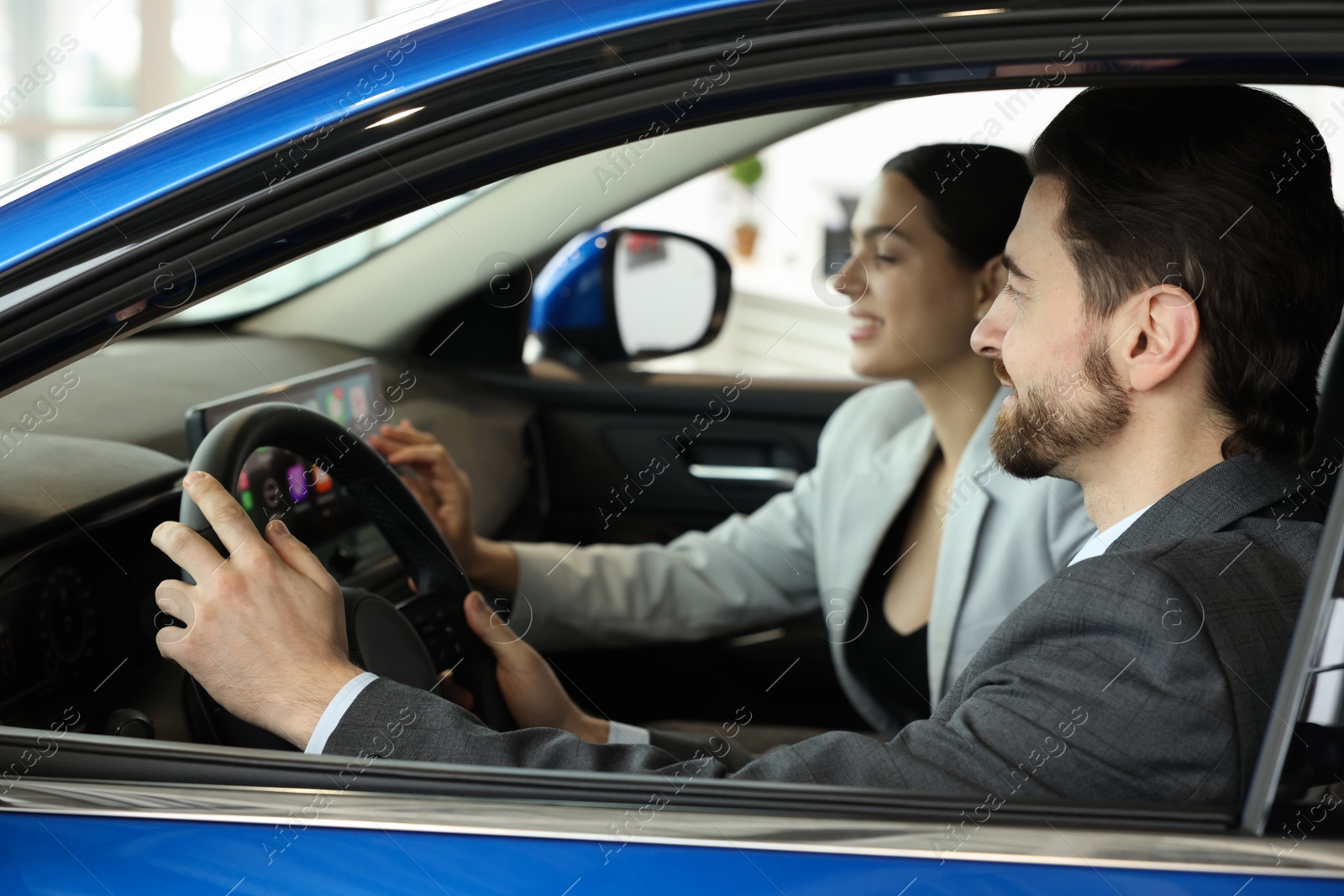 Photo of Happy saleswoman and client inside new car in salon, selective focus