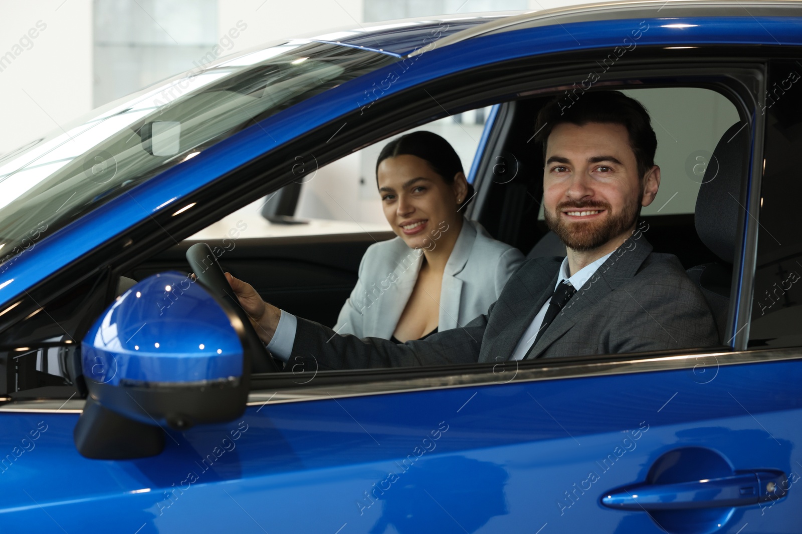 Photo of Happy saleswoman and client inside new car in salon