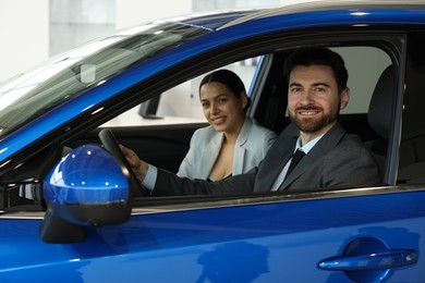 Happy saleswoman and client inside new car in salon