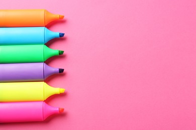 Photo of Bright highlighters on pink background, above view. Space for text