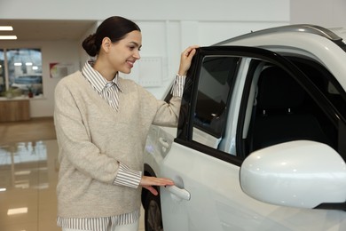 Happy woman near new white car in salon