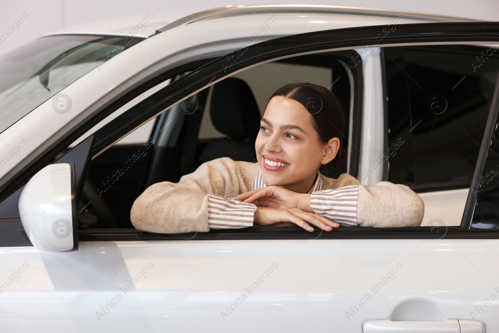 Photo of Happy woman inside new white car in salon