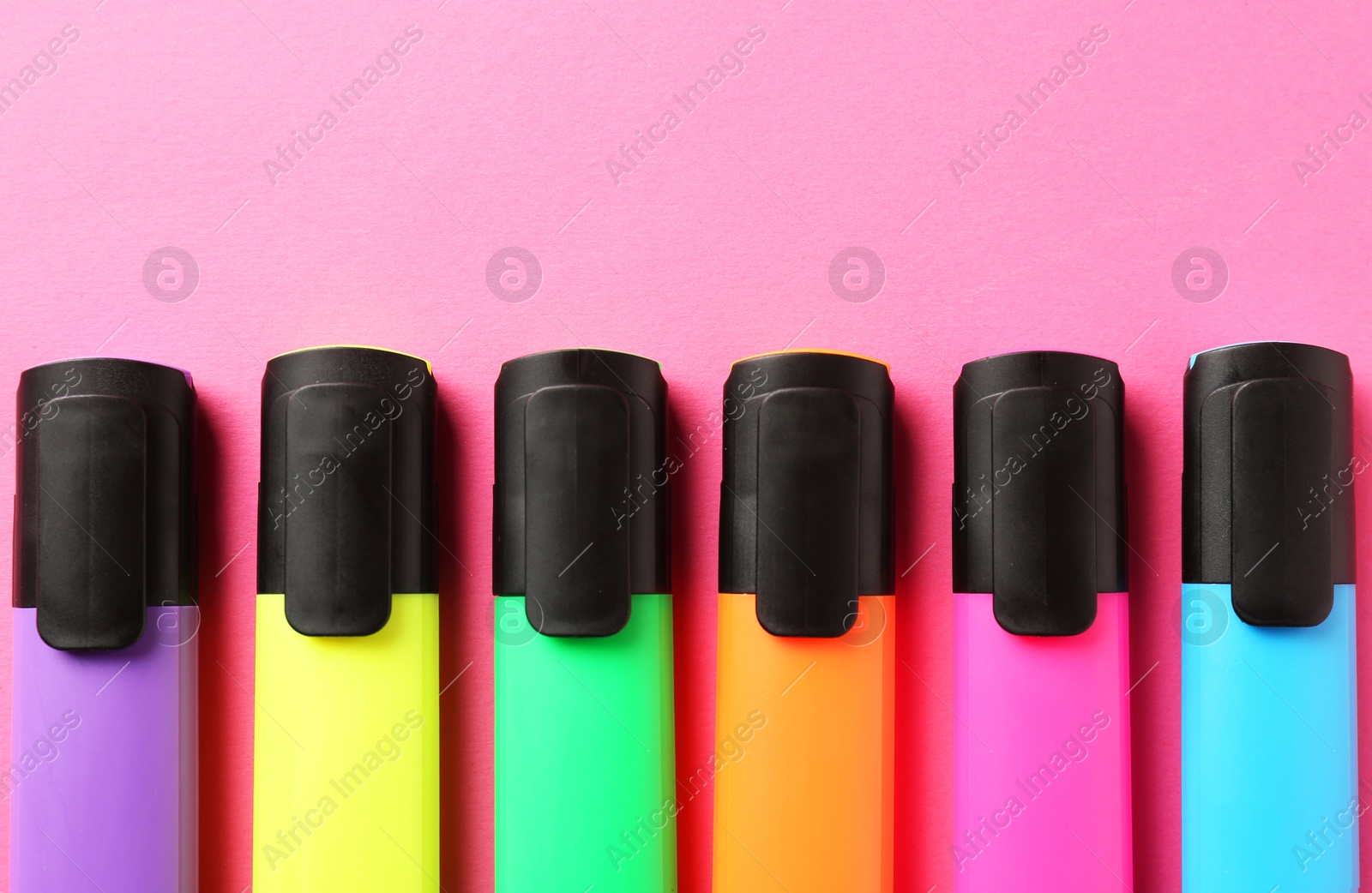 Photo of Bright highlighters on pink background, flat lay