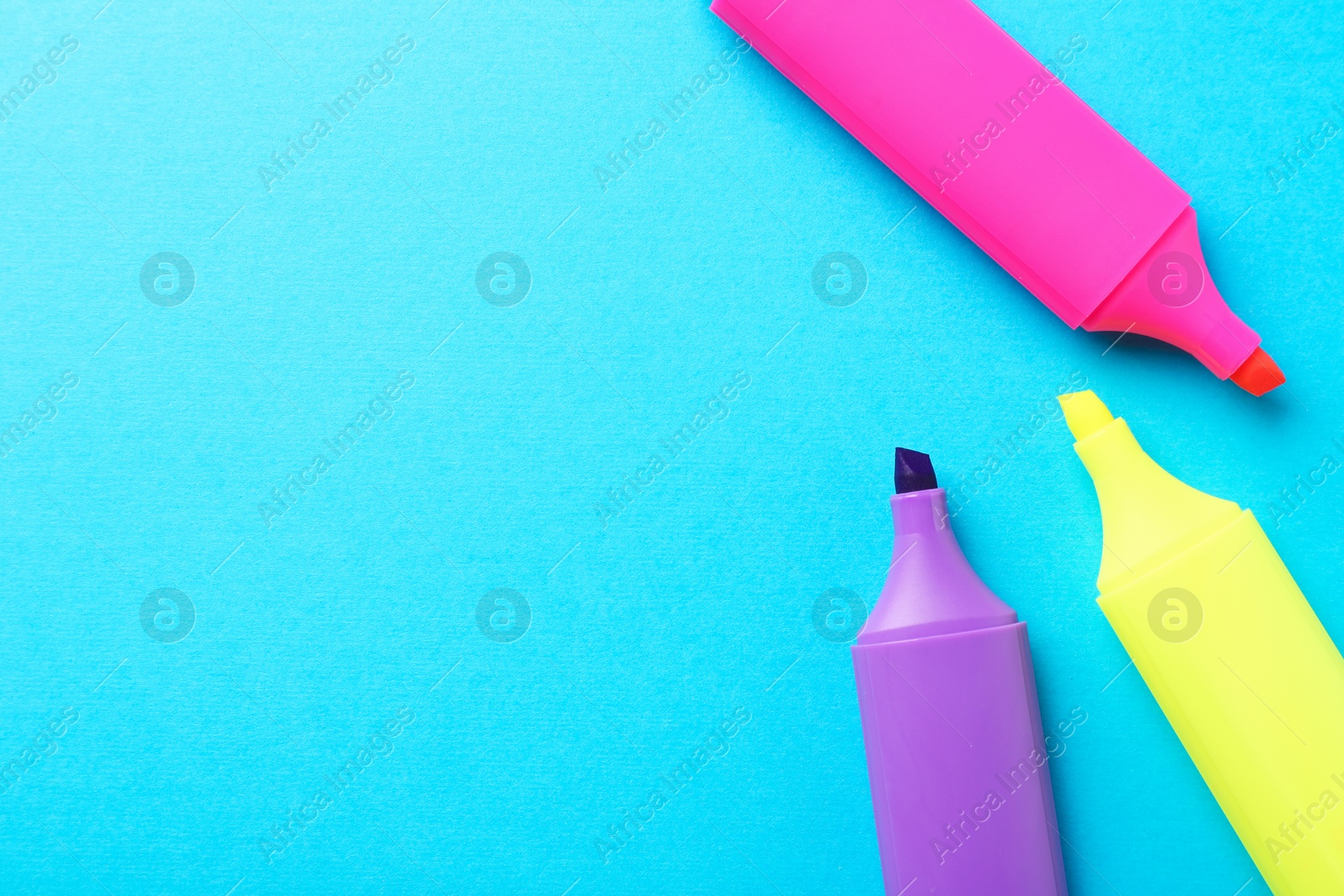 Photo of Bright highlighters on light blue background, flat lay. Space for text