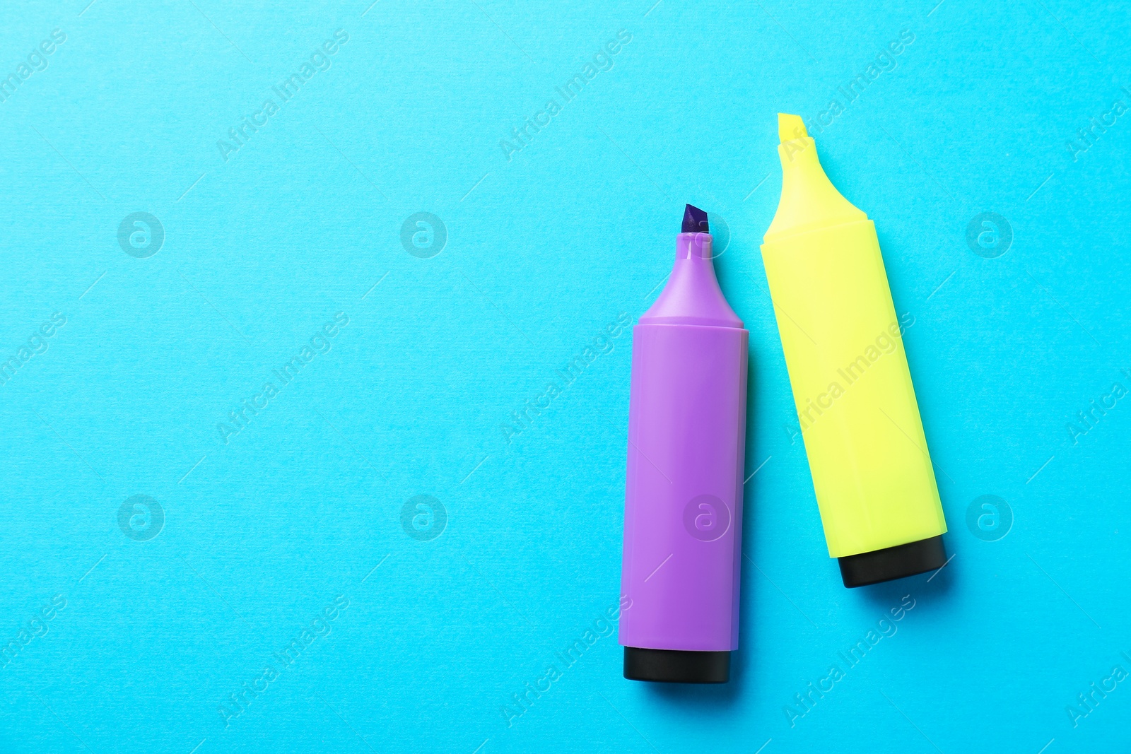 Photo of Bright highlighters on light blue background, flat lay. Space for text