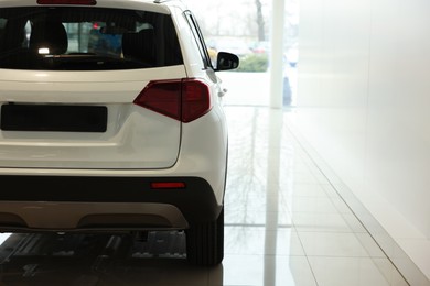 Photo of New modern white car in salon, space for text