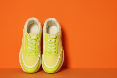 Photo of Stylish neon lime sneakers on color background, space for text