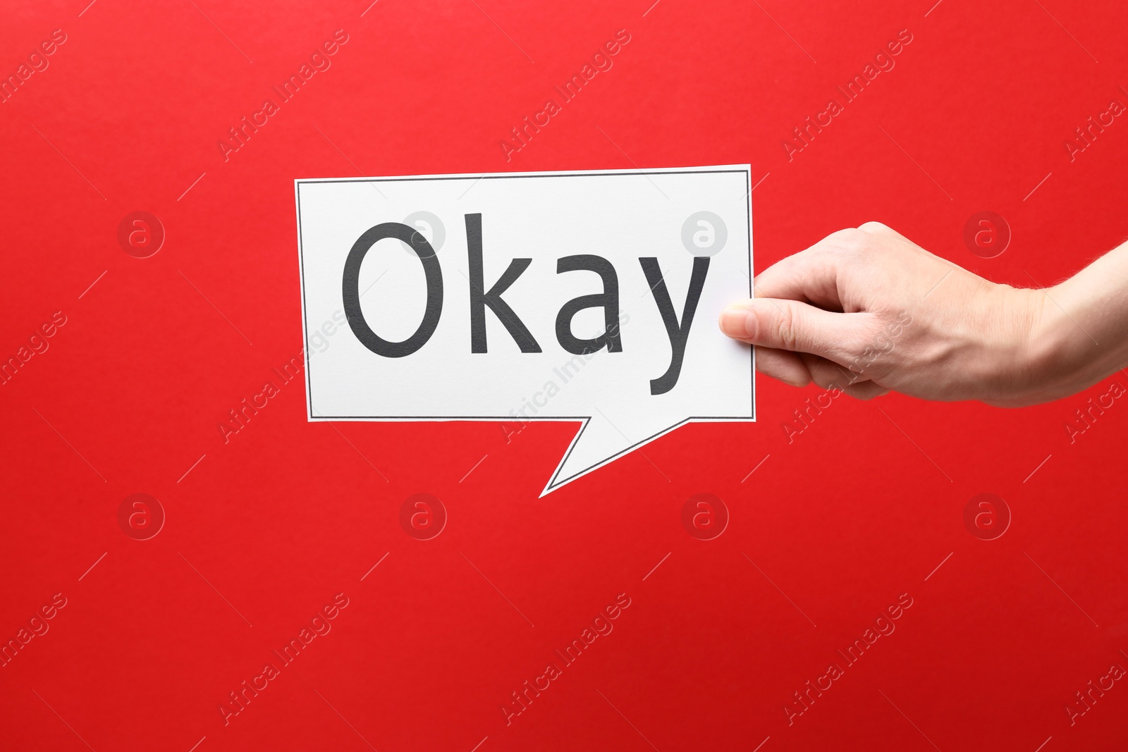 Image of Woman holding paper speech bubble with word Okay on red background, closeup