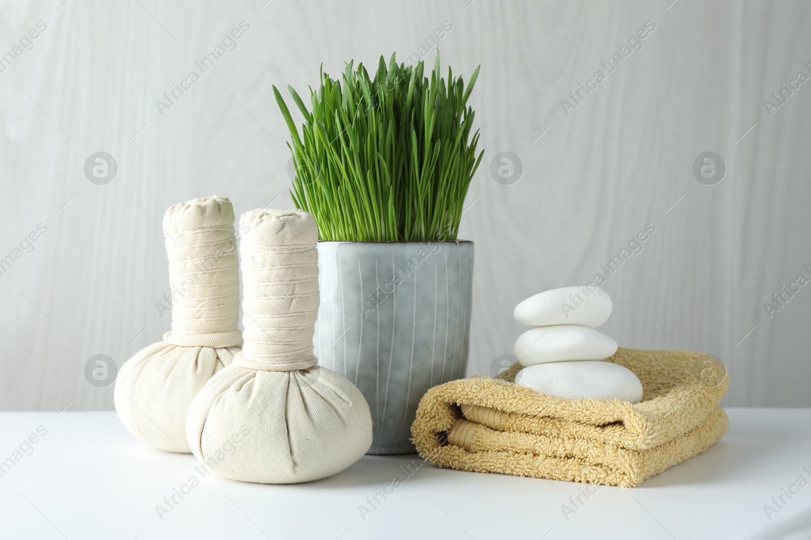 Photo of Spa composition with wheatgrass and herbal bags on white table