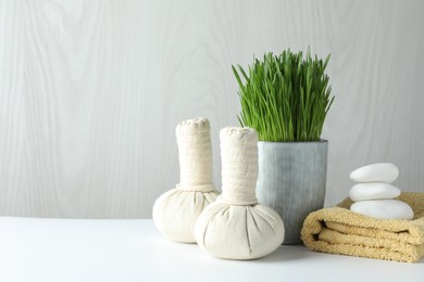 Spa composition with wheatgrass and herbal bags on white table. Space for text