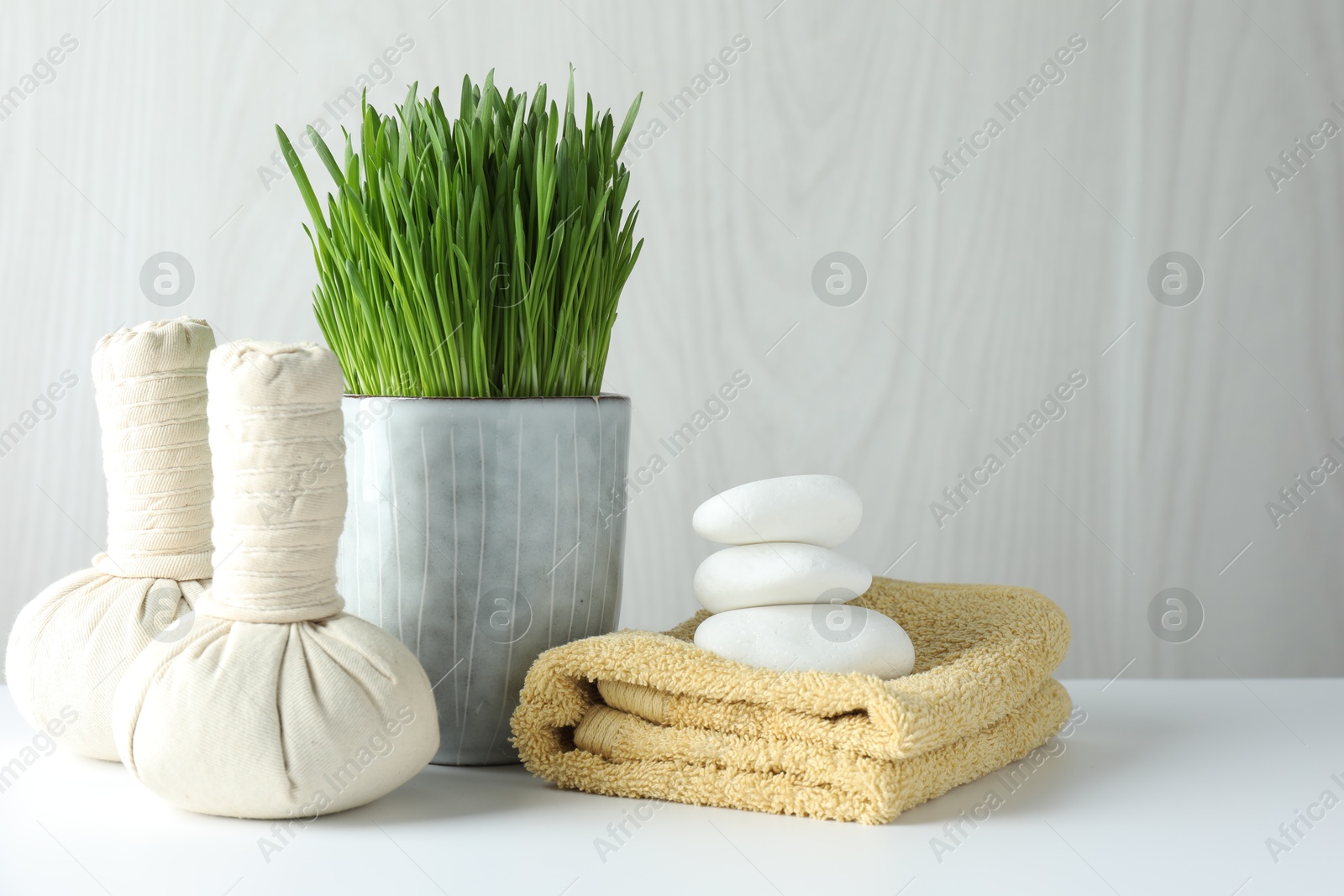 Photo of Spa composition with wheatgrass and herbal bags on white table. Space for text