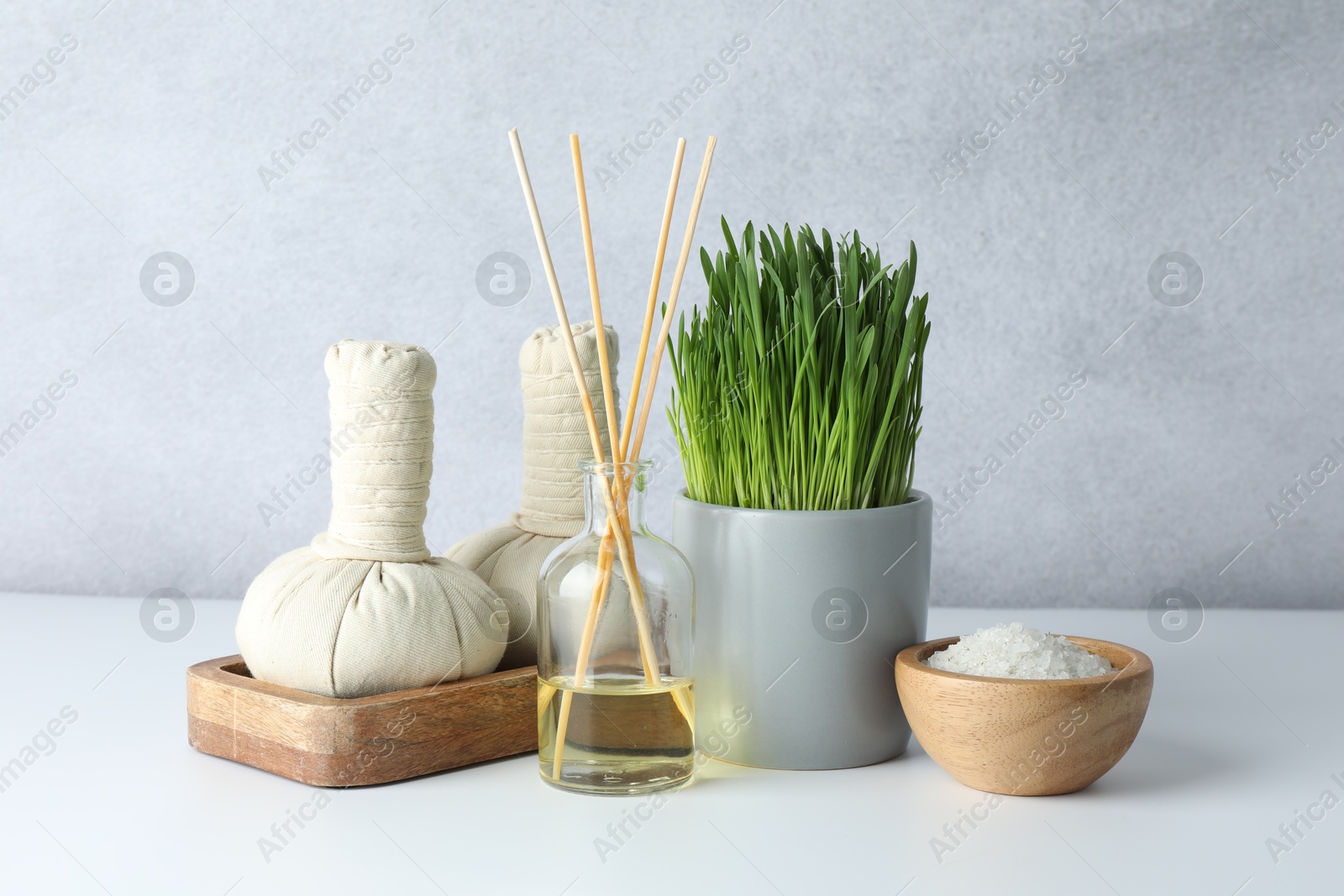 Photo of Spa composition with wheatgrass and herbal bags on white table