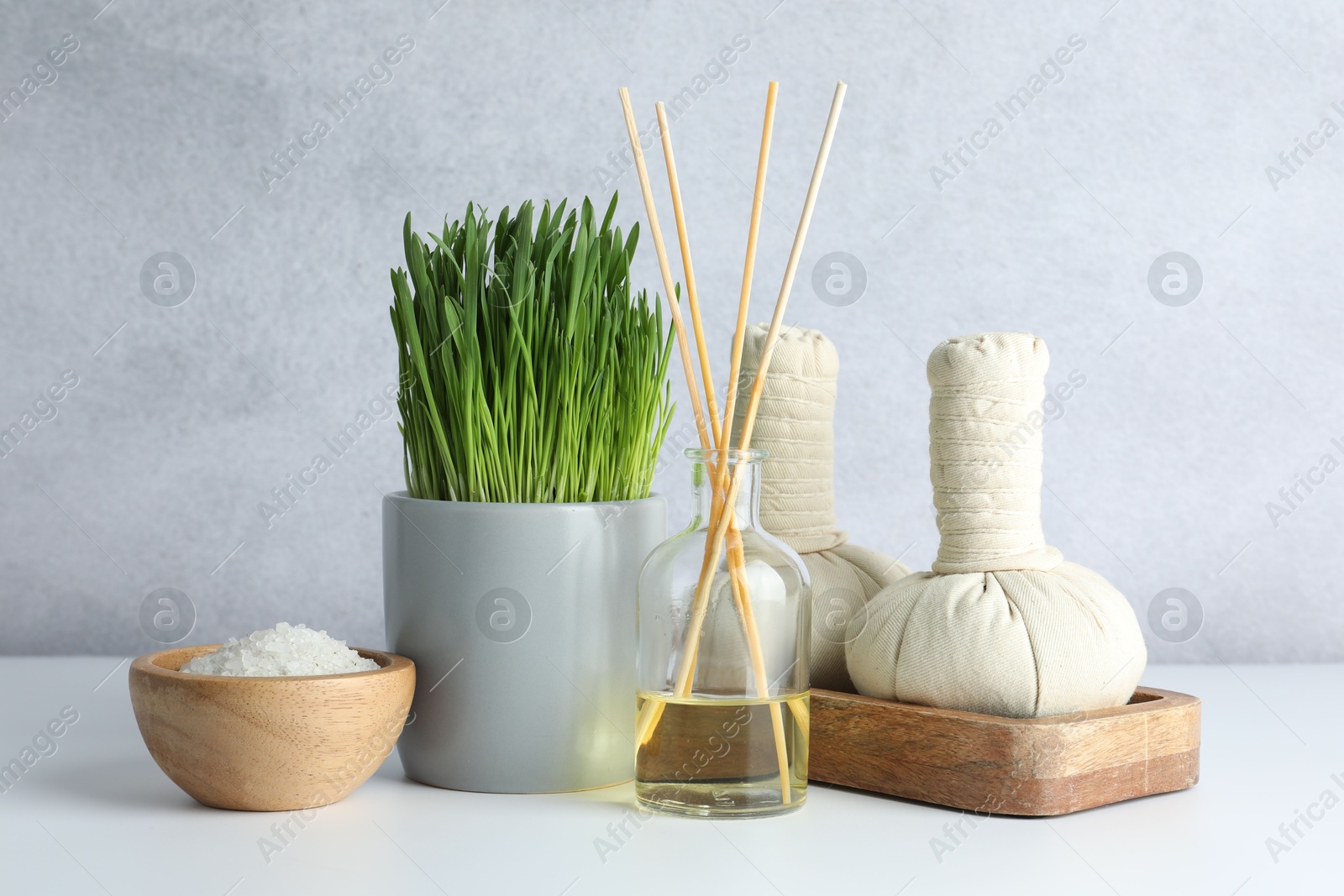 Photo of Spa composition with wheatgrass and herbal bags on white table