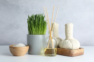 Photo of Spa composition with wheatgrass and herbal bags on white table