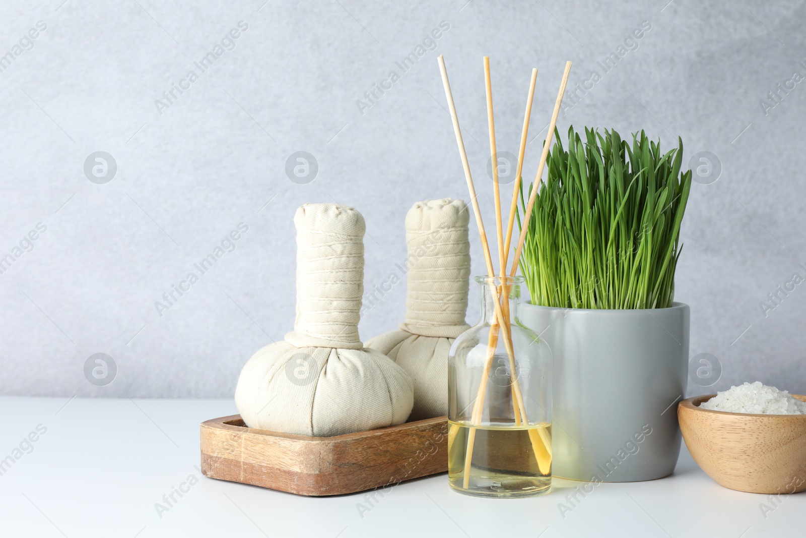 Photo of Spa composition with wheatgrass and herbal bags on white table. Space for text