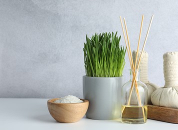 Photo of Spa composition with wheatgrass and herbal bags on white table. Space for text