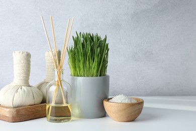 Photo of Spa composition with wheatgrass and herbal bags on white table. Space for text