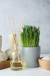 Photo of Spa composition with wheatgrass and herbal bags on white table